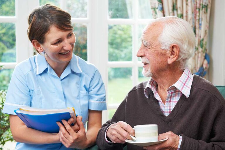 A senior resident smiles while greeting two family members in a comfortable assisted living lounge.