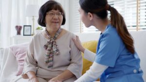 Older resident chooses clothing with a caregiver in a bright assisted living room.