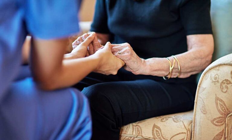 Older adult choosing clothing with a caregiver in a bright private assisted living room